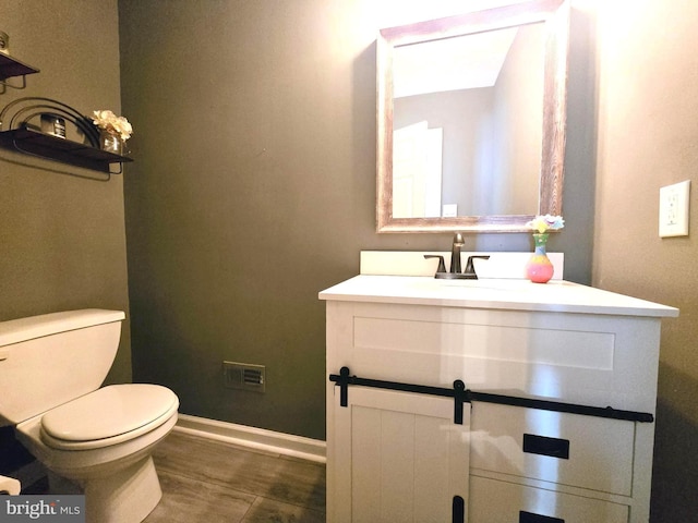 half bath featuring toilet, baseboards, and vanity