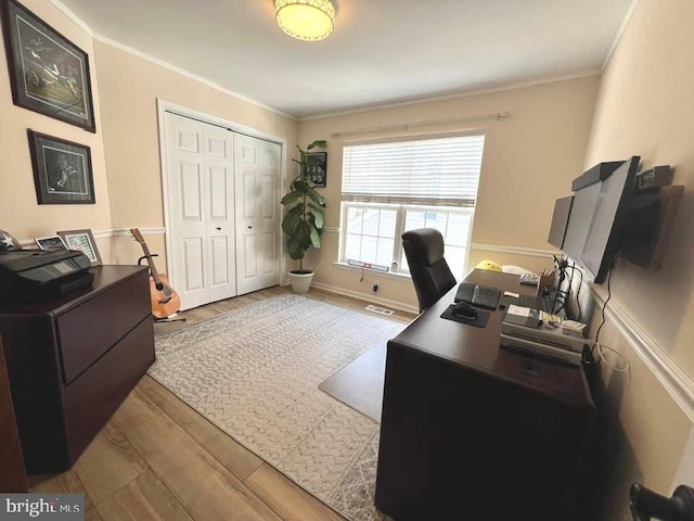 office area with baseboards, crown molding, visible vents, and wood finished floors