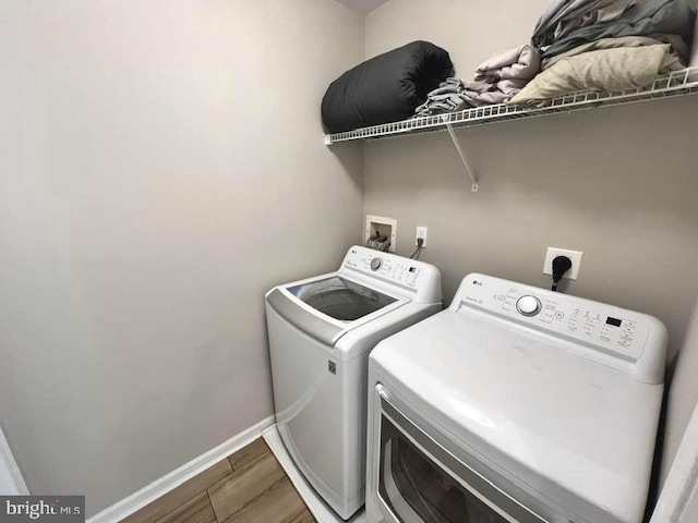 laundry area with washing machine and dryer, laundry area, baseboards, and wood finished floors