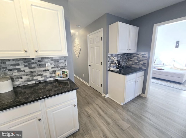 kitchen featuring light wood finished floors, baseboards, white cabinets, and backsplash