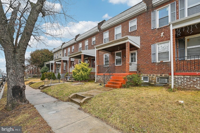 view of property featuring a porch, a front yard, and brick siding