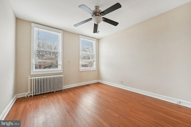 unfurnished room with baseboards, ceiling fan, radiator heating unit, and wood finished floors