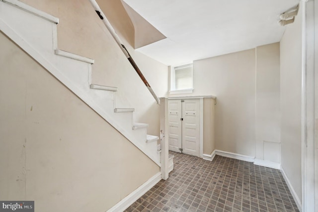 basement with baseboards and stairway