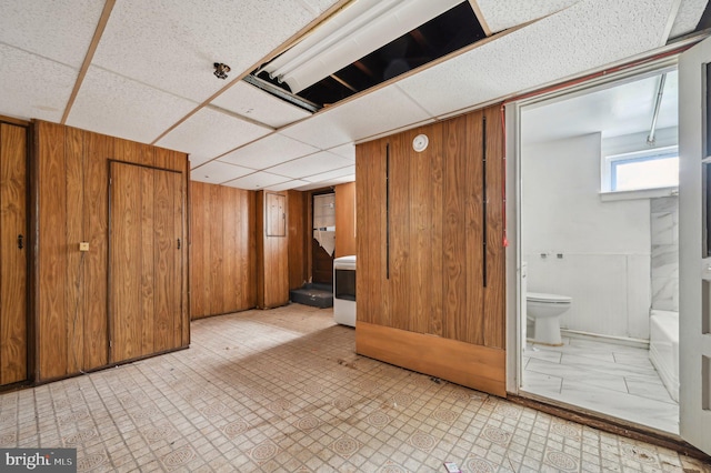 interior space with a paneled ceiling, wooden walls, and tile patterned floors