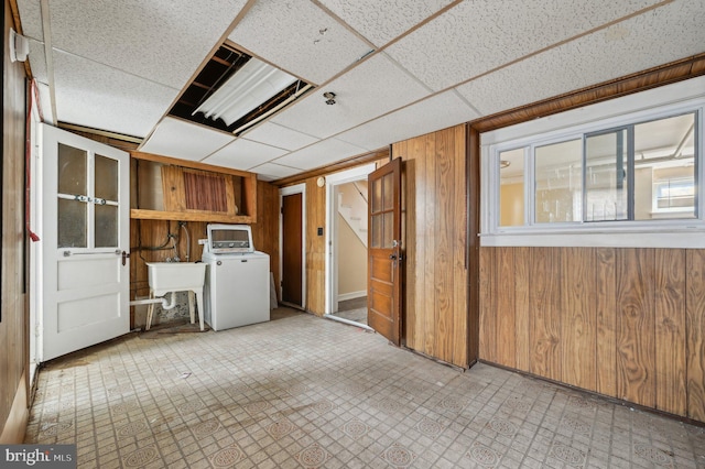 interior space with washer / clothes dryer, tile patterned floors, a paneled ceiling, wood walls, and a sink