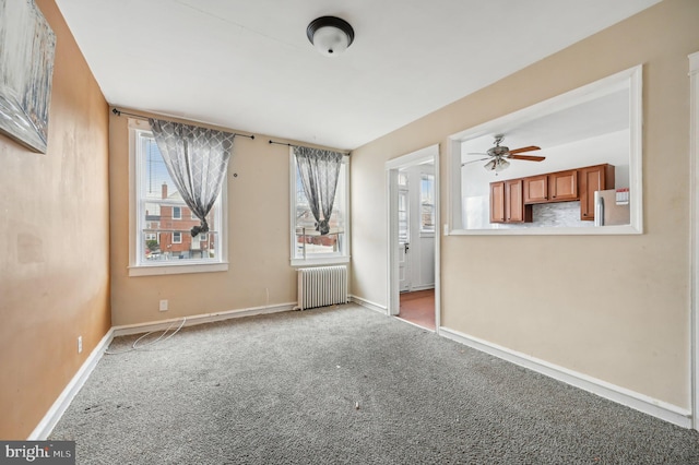 carpeted spare room featuring radiator and baseboards