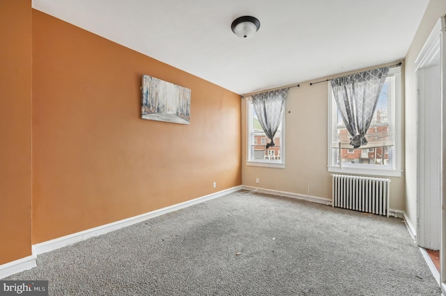 carpeted empty room featuring radiator heating unit and baseboards