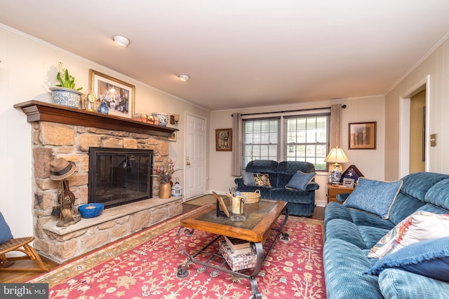 living area with ornamental molding, wood finished floors, and a stone fireplace