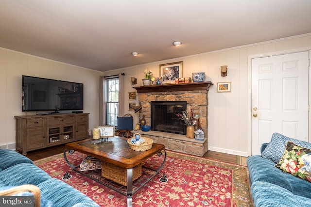 living area featuring ornamental molding, a stone fireplace, and wood finished floors