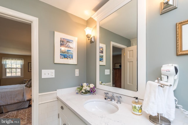 ensuite bathroom featuring wainscoting, connected bathroom, and vanity