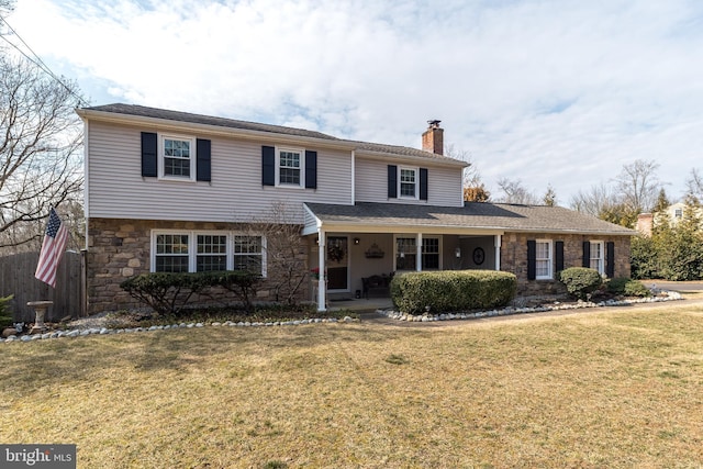 traditional home featuring stone siding, a front lawn, and a chimney