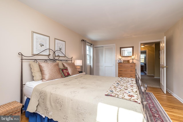 bedroom featuring a closet, light wood-style flooring, and baseboards