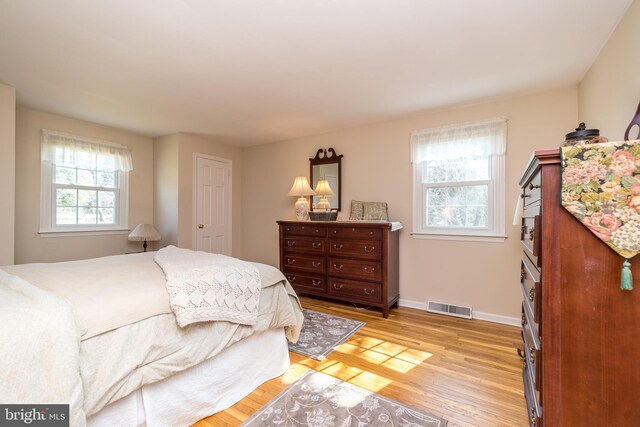 bedroom with light wood-style flooring, visible vents, and baseboards