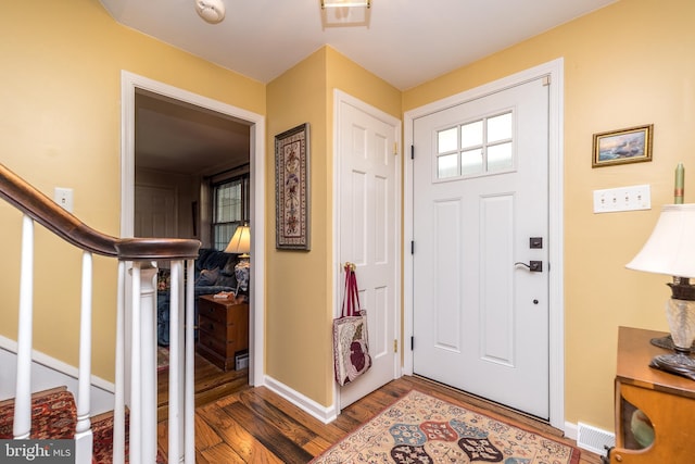 entryway with baseboards, visible vents, stairway, and wood finished floors