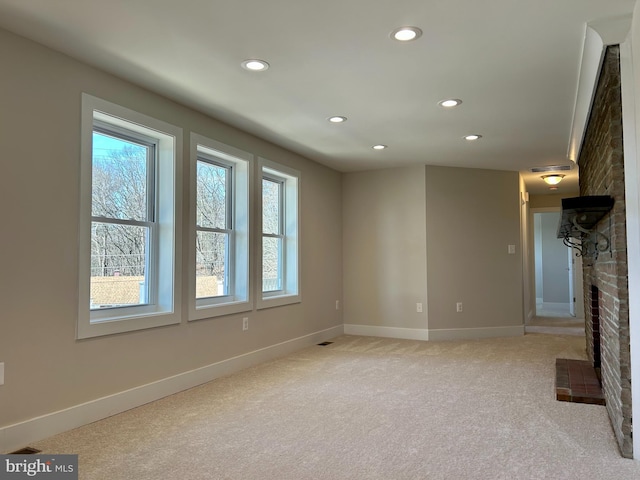 unfurnished living room featuring a healthy amount of sunlight, a brick fireplace, recessed lighting, and light colored carpet