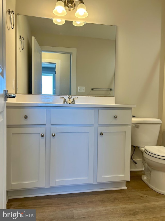 bathroom with vanity, toilet, and wood finished floors