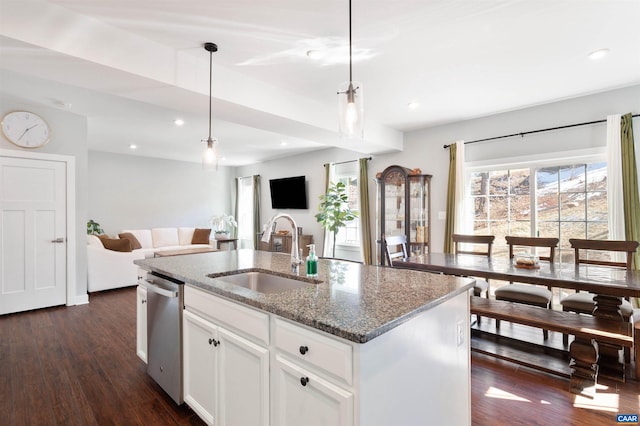 kitchen with a kitchen island with sink, a sink, white cabinetry, open floor plan, and hanging light fixtures