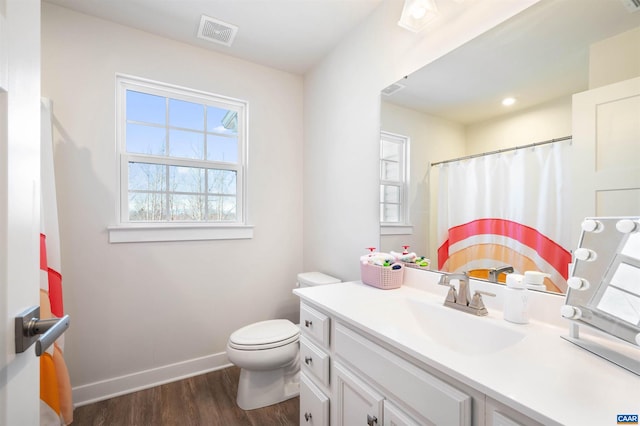 bathroom with toilet, wood finished floors, vanity, visible vents, and baseboards