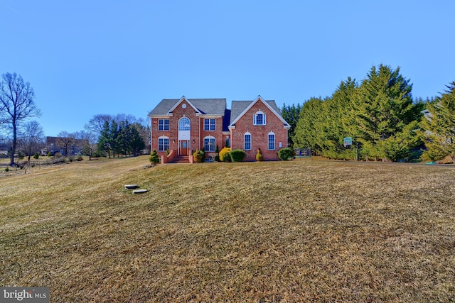 colonial house featuring a front yard and brick siding