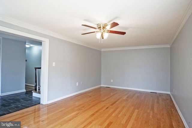 empty room with ceiling fan, wood finished floors, visible vents, baseboards, and crown molding