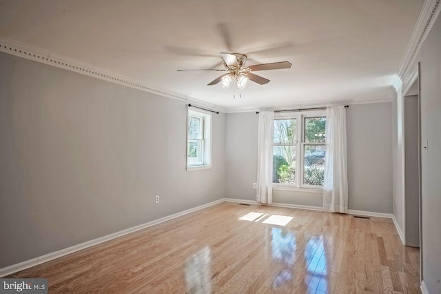 unfurnished room with ornamental molding, light wood-type flooring, a ceiling fan, and baseboards