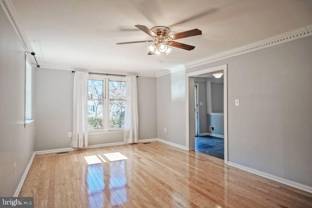 empty room with baseboards, wood finished floors, a ceiling fan, and crown molding