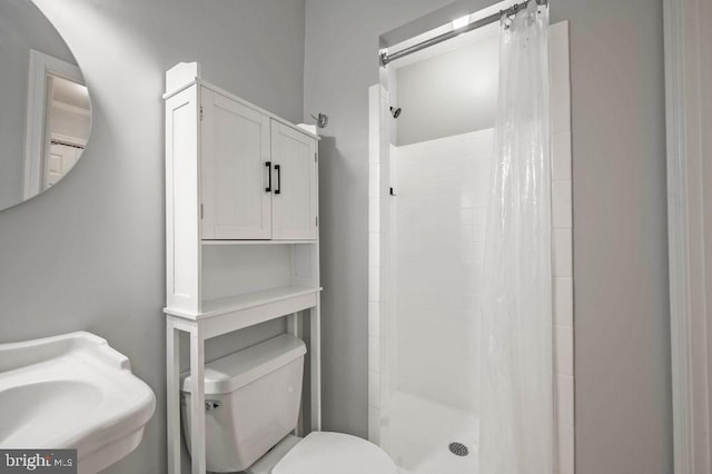 bathroom with toilet, a shower stall, and a sink