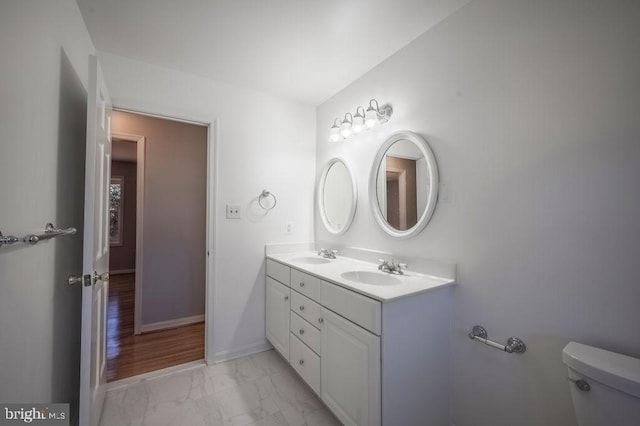 bathroom with marble finish floor, baseboards, a sink, and toilet