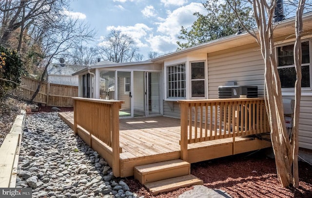 deck with a sunroom, fence, and cooling unit