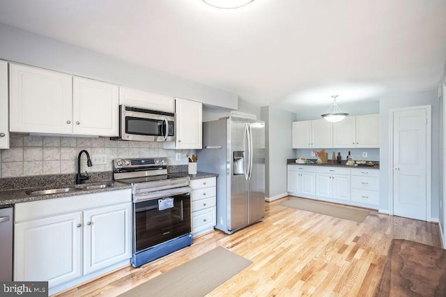 kitchen with light wood finished floors, white cabinetry, stainless steel appliances, and backsplash