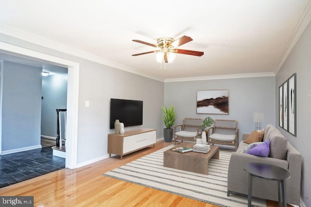 living area with baseboards, ceiling fan, wood finished floors, and crown molding