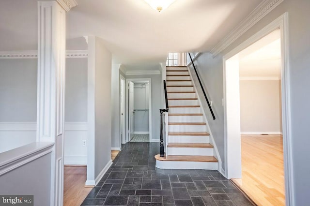 staircase featuring stone finish flooring, crown molding, and baseboards