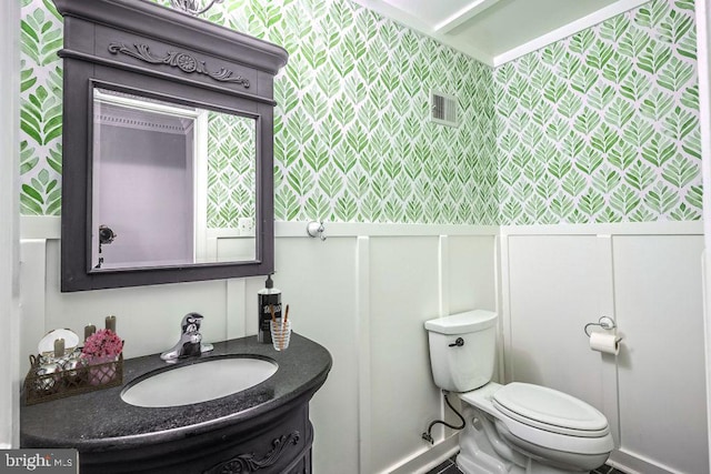 half bathroom featuring toilet, visible vents, and vanity