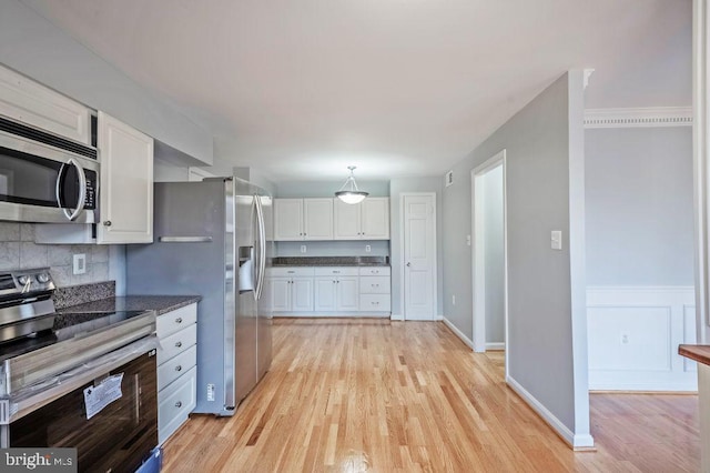 kitchen with pendant lighting, tasteful backsplash, light wood-style flooring, appliances with stainless steel finishes, and white cabinets