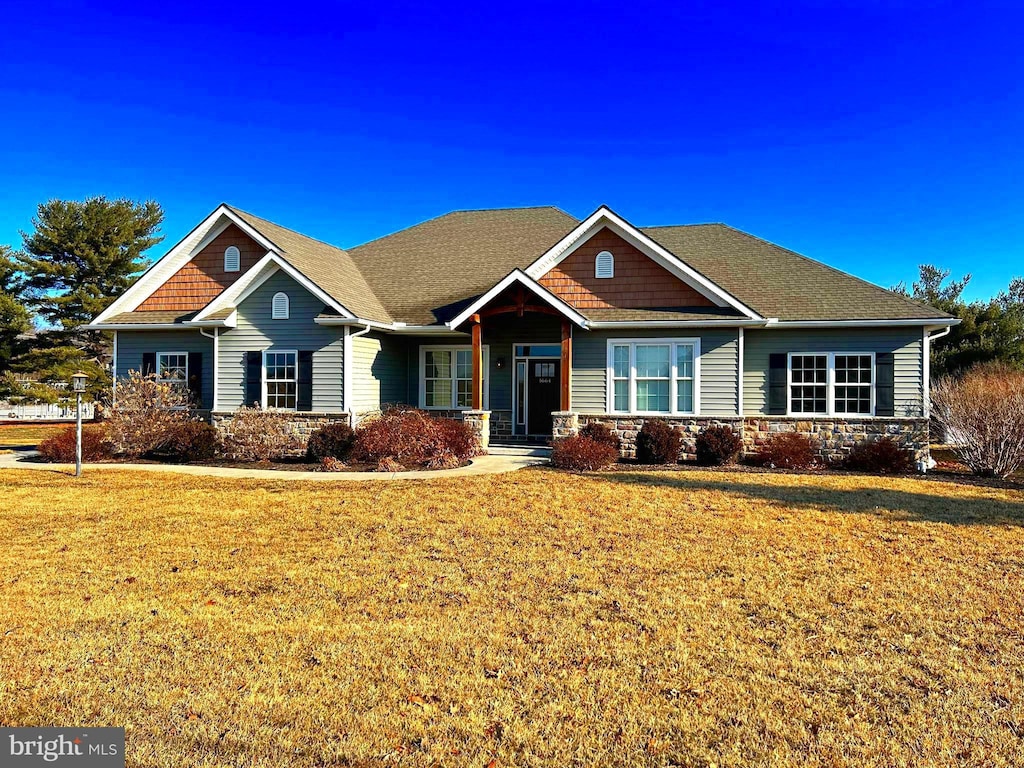 craftsman-style house with stone siding and a front lawn