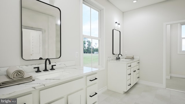 full bath with baseboards, two vanities, a sink, and recessed lighting