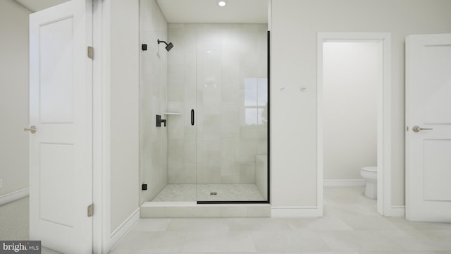 bathroom with a stall shower, toilet, and baseboards