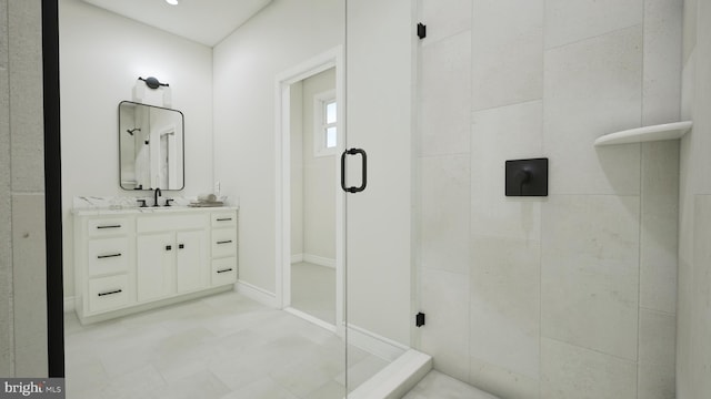 full bathroom with a stall shower, vanity, and baseboards