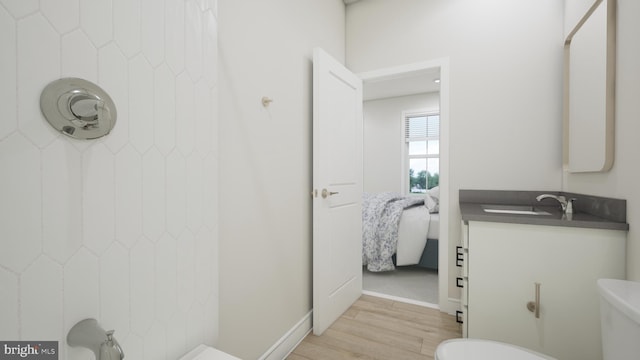 bathroom with toilet, wood finished floors, and vanity