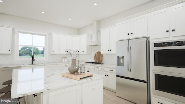 kitchen featuring appliances with stainless steel finishes, wall chimney range hood, white cabinets, and a kitchen breakfast bar