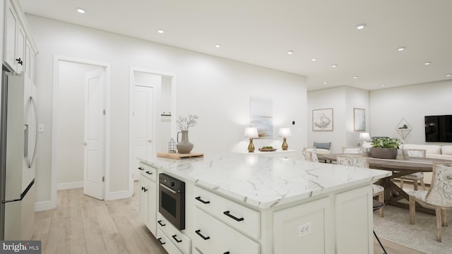 kitchen featuring light stone counters, open floor plan, white cabinetry, and refrigerator with ice dispenser