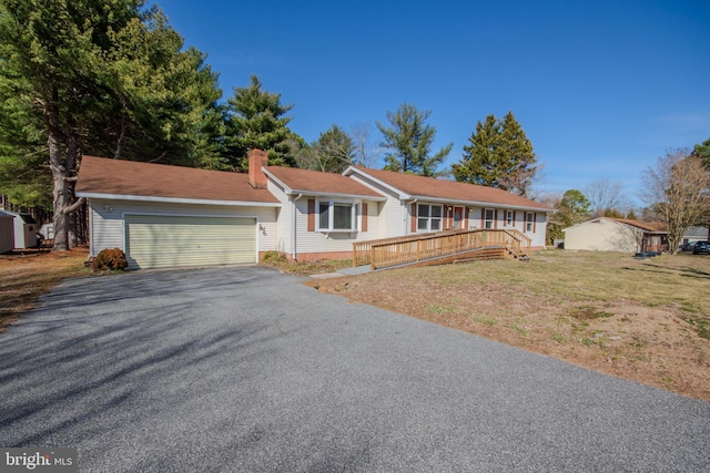 single story home with driveway, a front lawn, a chimney, and an attached garage