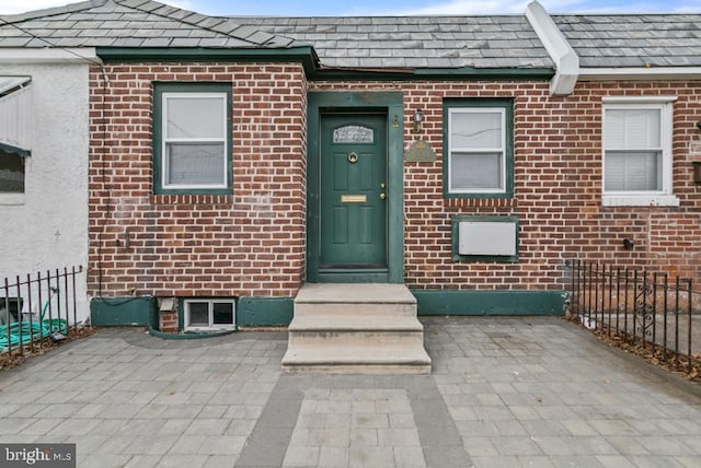 view of front of property with entry steps, brick siding, a patio, fence, and stucco siding