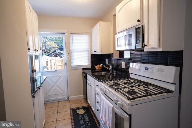 kitchen featuring white gas range, stainless steel microwave, decorative backsplash, white cabinetry, and a sink