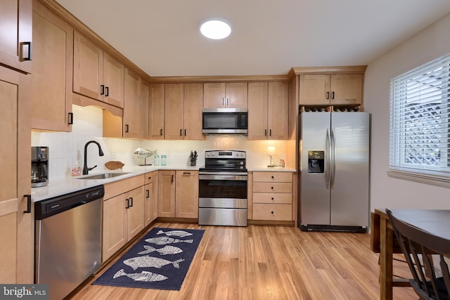 kitchen with appliances with stainless steel finishes, light countertops, a sink, and decorative backsplash