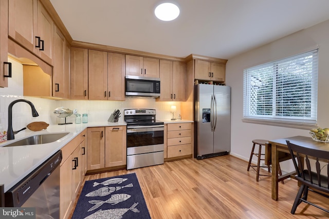 kitchen featuring tasteful backsplash, stainless steel appliances, a sink, and light brown cabinetry