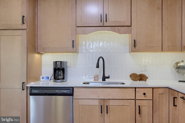 kitchen with light countertops, decorative backsplash, stainless steel dishwasher, light brown cabinets, and a sink