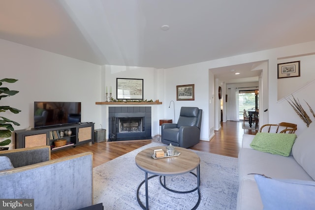 living room featuring a tiled fireplace and wood finished floors