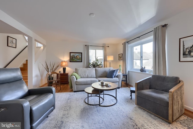 living room featuring stairs, baseboards, and wood finished floors