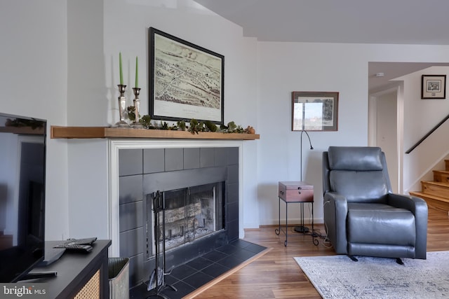 living area with wood finished floors, a fireplace, baseboards, and stairs